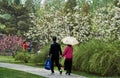 Beijing, China, April 12, 2017: Young Asian couple walking in park with an umbrella Royalty Free Stock Photo