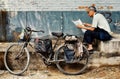 Man reading a newspaper next to his bicycle in a typical city hutong