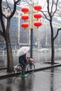 Person riding bicycles with an umbrella on a wet snowy day. Royalty Free Stock Photo