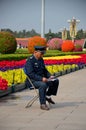 Chinese security guard reads in front of flower display Beijing China