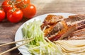 Beijing chinese Duck meat served with onions, pancakes, cucumber pieces and tomatoes on white plate with chopsticks close up. Wood Royalty Free Stock Photo