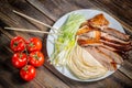 Beijing chinese Duck meat served with onions, pancakes, cucumber pieces and tomatoes on white plate with chopsticks close up. Wood Royalty Free Stock Photo