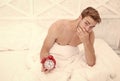 Being late this time. Unhappy man hold alarm clock. Late hours. Sexy guy awake in bed. Morning time. Staying in bed for Royalty Free Stock Photo