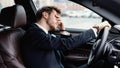 Sad young businessman driving alone in his new car