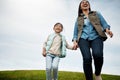 Being a mom is like walking on cloud nine. a woman holding her little girls hand as they walk outdoors. Royalty Free Stock Photo