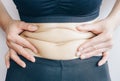 Close-up of Woman touching her fat belly, woman`s hand holding excessive belly fat.