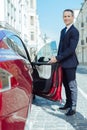 Handsome polite man opening the car door