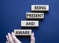 Being Present and Aware symbol. Wooden blocks with words Being Present and Aware. Doctor hand. Beautiful deep blue background.