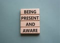 Being Present and Aware symbol. Wooden blocks with words Being Present and Aware. Doctor hand. Beautiful grey green background.