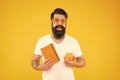 Being proud of geek in you. Geek man. Bearded man in geek glasses holding orange and book on yellow background. Hipster