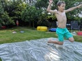 A young boy jumping onto a slip and slide Royalty Free Stock Photo