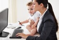 Being a working mom takes super powers. Working mother holding a baby while working on her computer. Royalty Free Stock Photo