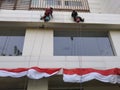 Bekasi, Indonesia, August 11, 2021 : Approaching Indonesia's independence day, workers are cleaning a building at a height Royalty Free Stock Photo