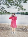 Bekasi, Indonesia, May 1, 2021: Asian woman wearing a red dress and face mask stands on a lake east of Bekasi