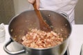 Bekon filling sauce cooking in big iron pan with hands Royalty Free Stock Photo