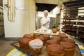 A bakery worker places trays with raw bread in the oven. Industrial production of bakery products