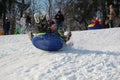 Parents and children ride from the snow slides in winter have fun resting in nature. Royalty Free Stock Photo