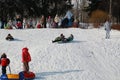 Parents and children ride from the snow slides in winter have fun resting in nature. Royalty Free Stock Photo