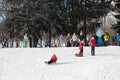 Parents and children ride from the snow slides in winter have fun resting in nature. Royalty Free Stock Photo