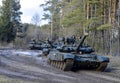 Russian armored combat vehicles are navigating through marshland through forests. Tankmen on the T-90