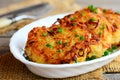 Roasted potato pancakes or draniki with ham slices and green onion on a white plate. Russian stuffed potato pancakes. Closeup