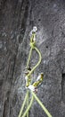 Belay stance for rock climbing in black granite with bolts carabiners and a yellow rope