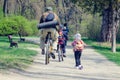 Belaya Tserkov, Ukraine - April 21, 2019: A man on a bicycle and a little girl on a scooter ride in the spring park Royalty Free Stock Photo