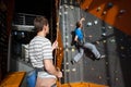 Belayer insuring the climber on rock wall indoors