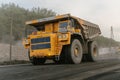 A BelAZ dump truck loaded with ore drives through an open pit mine.
