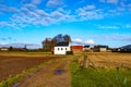 Belgian agricultural landscape with a dirt road between crop plots after harvest, chapel, farms in background Royalty Free Stock Photo