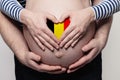 Belgian family concept. Man embracing pregnant woman belly and heart with flag of Belgium colors closeup Royalty Free Stock Photo