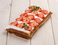 Belgian waffle with cream and strawberries. On a light wooden background