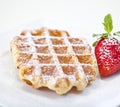 Belgian waffle with powedered sugar and a strawberry isolated on Royalty Free Stock Photo