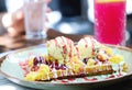 Belgian waffle with vanilla ice cream, strawberry sauce, custard and caramel on a plate on a restaurant table. Close up of Royalty Free Stock Photo