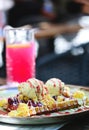 Belgian waffle with vanilla ice cream, strawberry sauce, custard and caramel on a plate on a restaurant table. Wholegrain flour Royalty Free Stock Photo