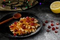 Belgian waffles on a black plate with cranberries, sprinkled with powder and honey. Dark background with garland.