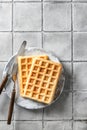 Belgian waffles with cutlery on gray tile background, space for text. Delisious savory or sweet breakfast. Top view