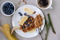 Belgian waffles with honey, blueberries, banana and almonds with a cup of fresh coffee