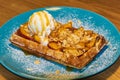 Belgian waffles with a scoop of white ice cream decorated with fruits and almonds.