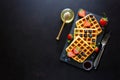 Belgian waffles with strawberries, blueberries and honey on slate plate on dark wooden background. Top view. Copy space Royalty Free Stock Photo