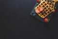 Belgian waffles with strawberries and blueberries on slate plate on dark wooden background. Royalty Free Stock Photo