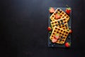 Belgian waffles with strawberries and blueberries on slate plate on dark wooden background. Top view. Copy space Royalty Free Stock Photo