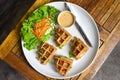Belgian waffles on white plate with greens on wooden background