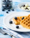 Belgian waffles on white plate on light blue background.. Royalty Free Stock Photo