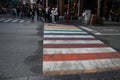 Pedestrian zebra road crossing with rainbow pattern painted between white lines.