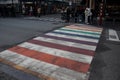 Pedestrian zebra road crossing with rainbow pattern painted between white lines.