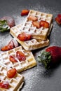 Belgium waffers with strawberries and sugar powder on black board