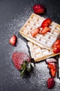 Belgium waffers with strawberries and sugar powder on black board