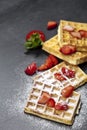 Belgium waffers with strawberries and sugar powder on black board background