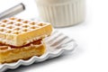 Belgium waffers with sugar powder on ceramic plate and strainer on white table